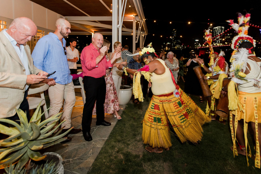 Guests dancing with the PNG dancers wearing bright yellow skirts